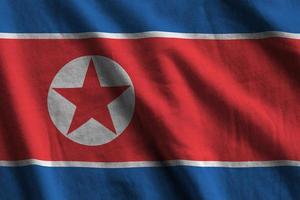 bandeira da coreia do norte com grandes dobras acenando perto sob a luz do estúdio dentro de casa. os símbolos e cores oficiais no banner foto