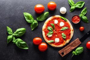 italiano pizza margherita com tomate molho mozzarella queijo manjericão em uma Sombrio concreto fundo. pizza receita e cardápio. foto