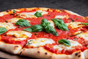 italiano pizza margherita com tomate molho mozzarella queijo manjericão em uma Sombrio concreto fundo. pizza receita e cardápio. foto