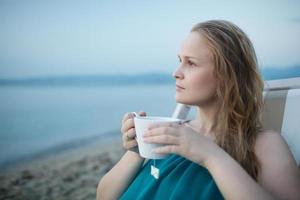 mulher tomando uma xícara de chá na praia foto