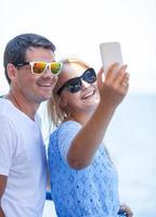 casal alegre de óculos escuros tirando uma selfie foto