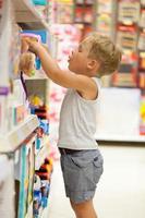 menino escolhendo um brinquedo em uma loja foto