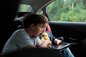 meninos usando um tablet em um carro foto