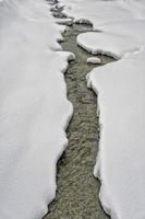 Riacho fluindo dentro neve fundo foto