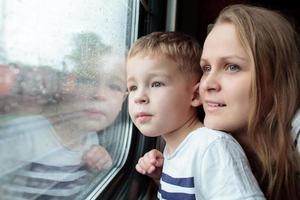 mãe e filho olhando pela janela de um trem
