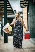 retrato de uma jovem mulher feliz com sacolas de compras, andando na rua