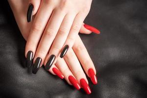 mãos de uma jovem com manicure preto e vermelho nas unhas foto