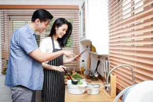 casais asiáticos cozinham juntos em suas cozinhas domésticas. conceito de vida durante covid-19, distância social, copie o espaço foto