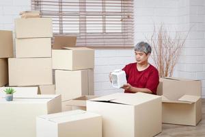 gordo homem com branco cabelo é embalagem produtos para dentro papel caixas para Entrega a conceito do pequeno empresários, conectados negociação negócios, entregar bens de enviar foto