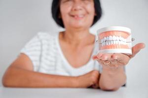 as mulheres asiáticas idosas seguram modelos de dentaduras. conceitos de problemas de saúde bucal sênior e atendimento odontológico