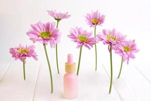 Cosmético garrafa em de madeira mesa com Rosa margarida flores foto