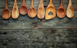 utensílios de cozinha de madeira em um fundo de madeira surrado foto