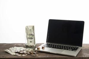 laptop com moedas e banco do dólar isolado no fundo branco foto