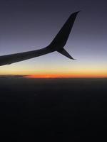uma asa de avião durante o pôr do sol foto