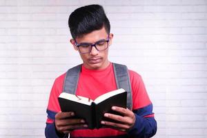 homem segurando um livro sobre fundo de tijolos foto