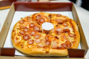 clássico pizza com queijo em a mesa dentro uma cafeteria em uma de madeira ficar de pé com uma cortar triangular peça e uma pizza faca foto