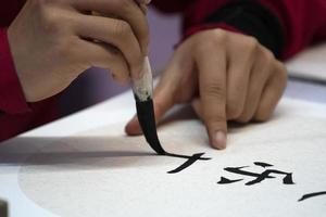 japonês mulher escrevendo nome Charles dentro ideogramas com escova foto