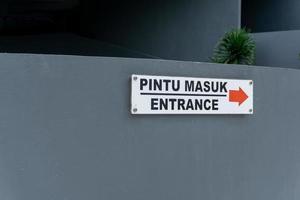 pintu masuk significar Entrada. Entrada placa em a parede escrevi dentro bahasa pintu masuk foto