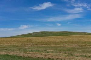 paisagem com campos e colinas e céu azul nublado foto