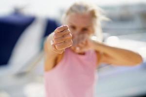 mulher mais velha fazendo boxe de sombra ao ar livre. fêmea sênior fazendo esporte em um porto costeiro foto