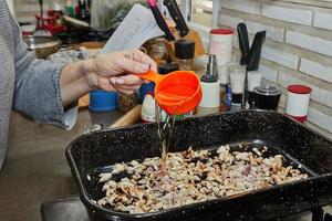 cozinhar derrama óleo para dentro cogumelos com cebolas dentro quadrado fritar panela foto