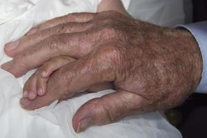 mãos de velho aposentado segurando um recém-nascido foto