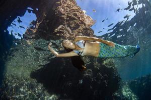 sereia nadando debaixo d'água no mar azul profundo foto