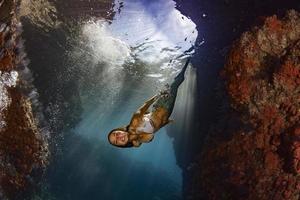 sereia nadando debaixo d'água no mar azul profundo foto