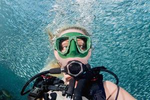 beleza loira menina mergulhadora olhando para você enquanto nadava debaixo d'água foto