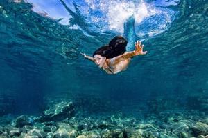 sereia nadando debaixo d'água no mar azul profundo foto