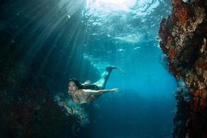 sereia nadando debaixo d'água no mar azul profundo foto