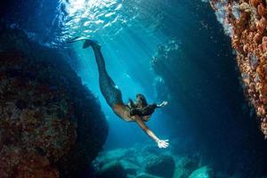 sereia nadando debaixo d'água no mar azul profundo foto