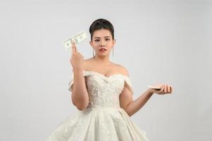 jovem noiva linda asiática segurando notas de dólar na mão foto