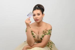 jovem noiva linda asiática postando com cartão de crédito na mão foto