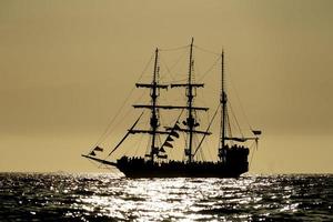 pirata navio silhueta às pôr do sol às a aberto mar às a pôr do sol foto