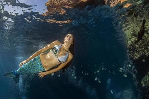 sereia nadando debaixo d'água no mar azul profundo foto