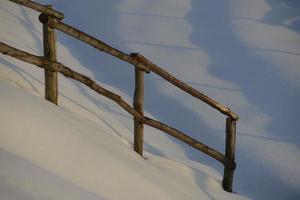 uma madeira cerca sobre branco neve fundo dentro inverno Tempo foto