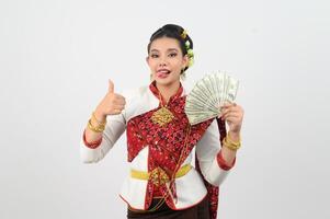 retrato do lindo tailandês mulher dentro tradicional roupas posando com ventilador nota de banco foto