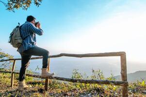 homem jovem mochileiro usa câmera para tirar fotos na floresta.