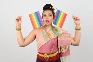 retrato do jovem mulher dentro tailandês nordeste tradicional roupas segurando arco Iris bandeira foto