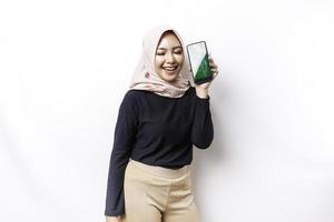 uma retrato do uma feliz ásia muçulmano mulher vestindo uma hijab, mostrando dela telefone tela, isolado de branco fundo foto