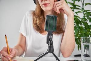 mulher gravando podcast online em casa. microfone na mesa. local de trabalho do home studio foto