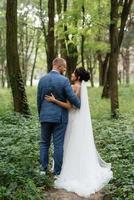 Casamento andar do a noiva e noivo dentro a decíduo floresta dentro verão foto