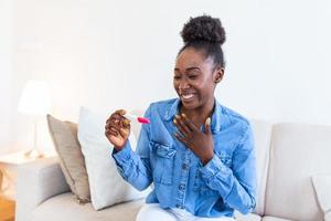 jovem mulher olhando às gravidez teste resultado com positivo sorriso, feliz este ela é indo para ter bebê. finalmente grávida. foto