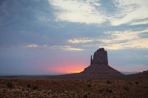 vista do vale do monumento ao pôr do sol com céu nublado maravilhoso e luzes nas luvas foto