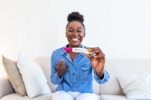 jovem feliz mulher segurando positivo gravidez teste, raso profundidade do campo. feliz este ela é indo para ter bebê. finalmente grávida. foto