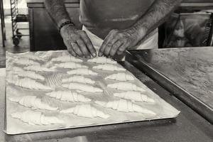 mãos preparando croissant francês em preto e branco foto