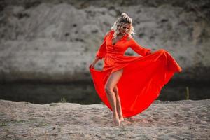 lindo mulher dentro laranja vestir posando às a fundo do areia Colina foto