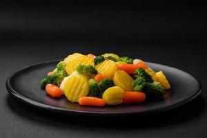 delicioso fresco legumes cozido no vapor cenouras, brócolis, couve-flor em uma Preto prato foto