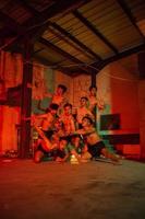 uma grupo do homens sem roupas dançando poses dentro a velho construção com uma vermelho luz foto